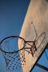 Old basketball hoop with blue sky.