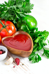 Tomato ketchup and ingredients on a white background