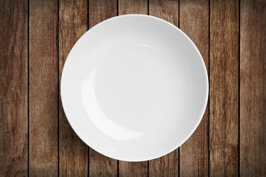 Simple white circular porcelain plate on wood with clipping path