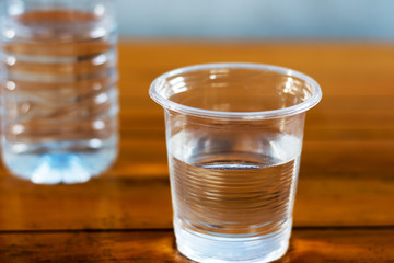 Drinking water in the glass and in the bottle on a wooden table.