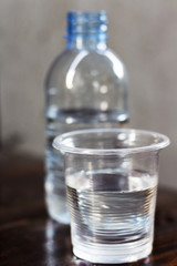 Drinking water in the glass and in the bottle on a wooden table.