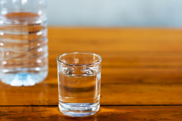 Drinking water in the glass and in the bottle on a wooden table.