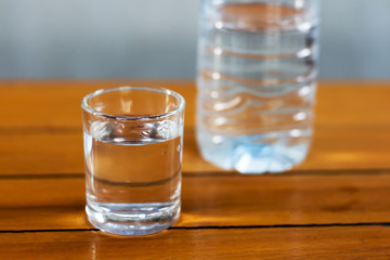 Drinking water in the glass and in the bottle on a wooden table.