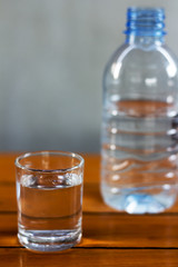 Drinking water in the glass and in the bottle on a wooden table.