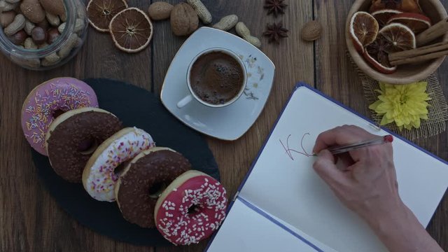 4k Donuts Composition on a Wooden Background with a hand writing Kcal?