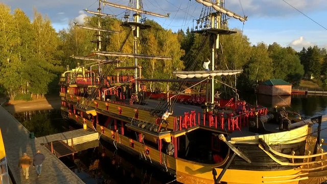 Aerial flying towards traditional Dutch sailing ship then moving around it drone boat moving slowly forward over the quiet water overcast weather grey cloud and not much wind classic medieval build 4k