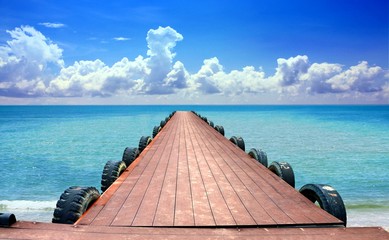 Jetty at the beach with cloudy blue sky