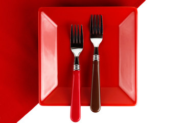 Red plate and two forks on a red napkin.