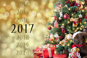 Year 2017 text card with gold shining background and magical Christmas tree.