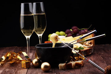 Gourmet Swiss fondue dinner on a winter evening with assorted cheeses on a board alongside a heated...
