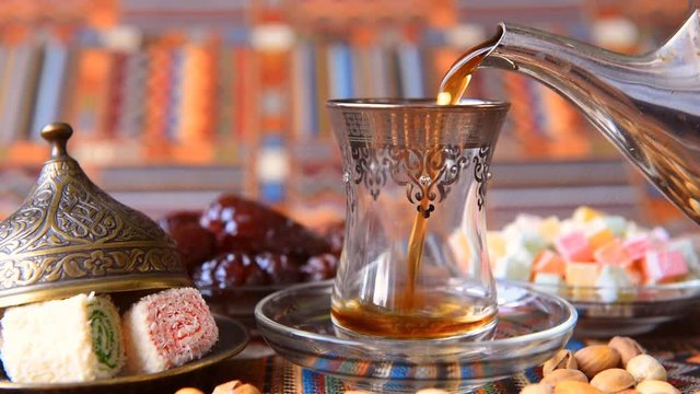 Turkish tea poured from a metal teapot in traditional dishes 