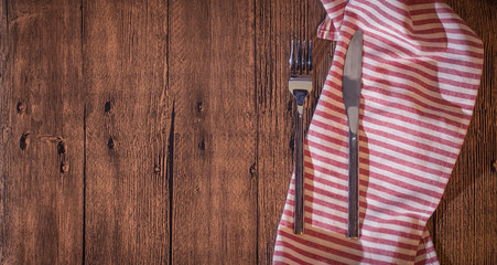 Fork and knife on wooden table with kitchen towel.Top view