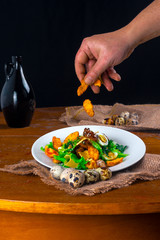 salad preparation - adding croutons in a warm salad of chicken breast, quail eggs and herbs and fried mushrooms