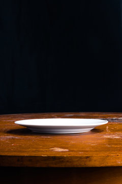 empty white plate on an old table side view