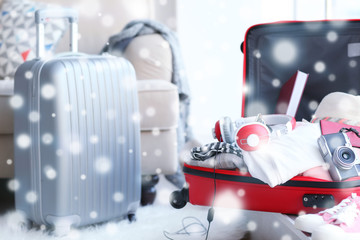 Winter vacation concept. Snowy effect on background. Packing luggage at home