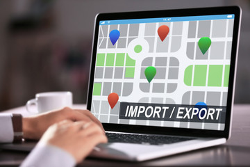 Logistics concept. Man with laptop, closeup. Text IMPORT/EXPORT and map on screen