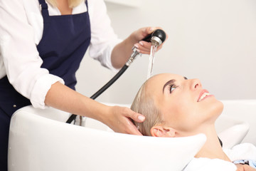 Obraz na płótnie Canvas Hairdresser washing woman's hair in salon