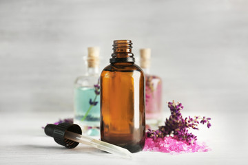 Bottles with lavender oil and flowers on wooden background