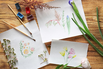 Watercolor painting with flowers on wooden table