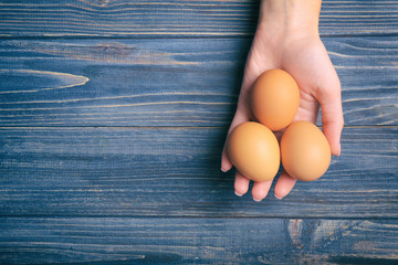 Woman holding raw eggs on wooden background