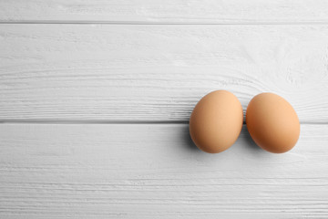 Two raw eggs on wooden background