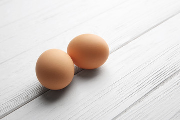 Two raw eggs on wooden background, closeup