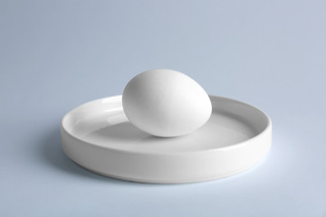 Raw egg on plate on white background