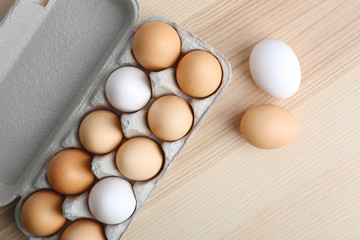 Raw eggs in package on wooden table