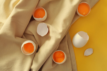 Raw cracked eggs on tablecloth