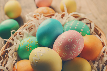 Wicker basket with colourful Easter eggs, closeup