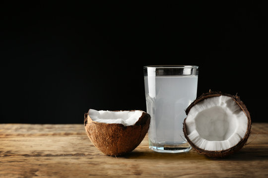 Glass of coconut water with nut on wooden table
