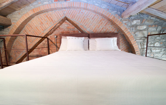 front view of king size bed on a mezzanine in a rustic loft