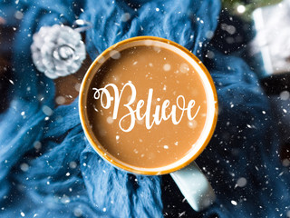 Mug of coffee and milk on dark blue winter background. Selective focus. Falling snow effect. Believe in your dreams concept