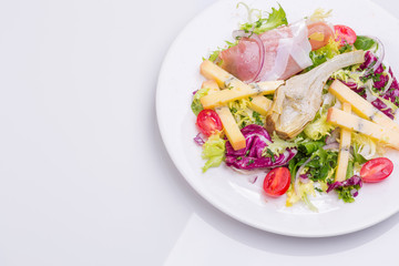 European cuisine dish salad from vegetables, cheese and ham. food on a white plate and a top view of a light background