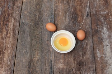 Raw egg in a bowl selective focus on wooden table