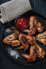 Above view of grilled chicken wings with sauce in a frying pan