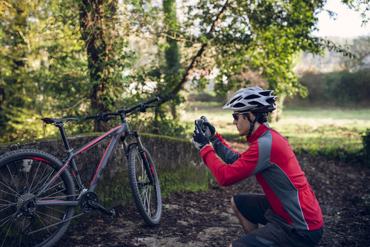 Mountain biker taking picture in forest with his smart phone
