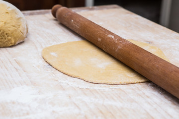 Impasto lavorato a mano e mattarello su tavola da legno 
