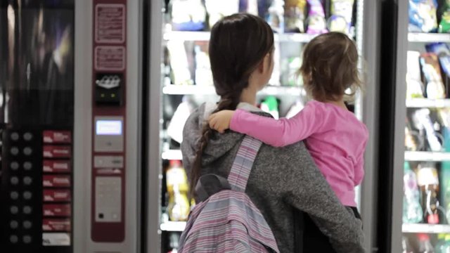 Mother and daughter selecting a snacks at vending machine inside airport