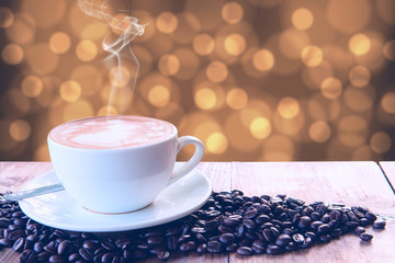 Coffee cup and coffee beans on the wooden table and brown bokeh