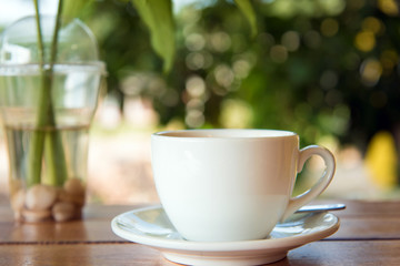 cup of fresh coffee with coffee beans on wooden table
