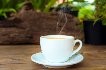 cup of fresh coffee with coffee beans on wooden table