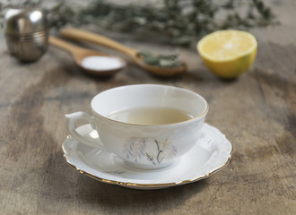 Cup of tea with mint and tea strainer on old wooden table. Selec