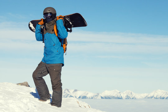 Male snowboarder taking a look at landscape while climbing to the top of the mountain