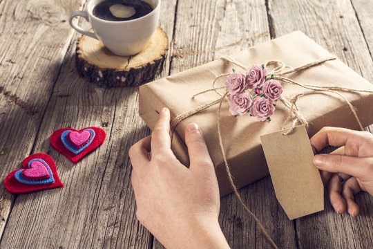 Woman hands holding gift on wooden background