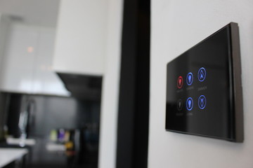 Electronic touch screen light and temperature control panel wall mounted in a modern apartment room.