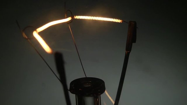 Dettaglio del filamento di una vecchia lampada al tungsteno che si accende e si spegne.