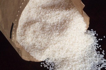 White rice in paper bag on wood background