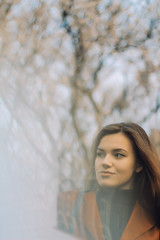 girl in a red jacket and black turtleneck with flowing hair on the background of a blossoming tree in the spring  