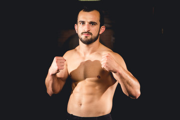 Fototapeta na wymiar Athlete standing in a boxing guard isolated with a dark background